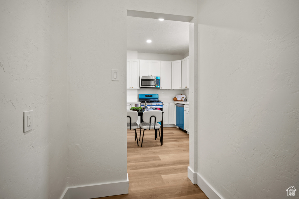 Hall featuring light wood-style floors and a textured wall