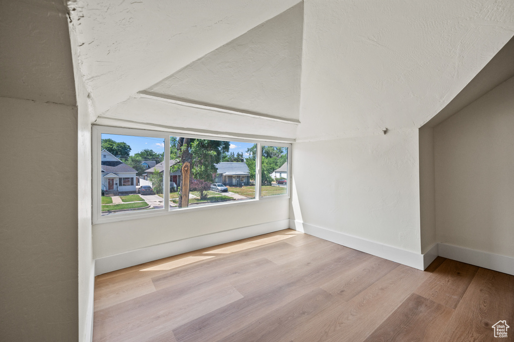 Spare room featuring wood finished floors and lofted ceiling