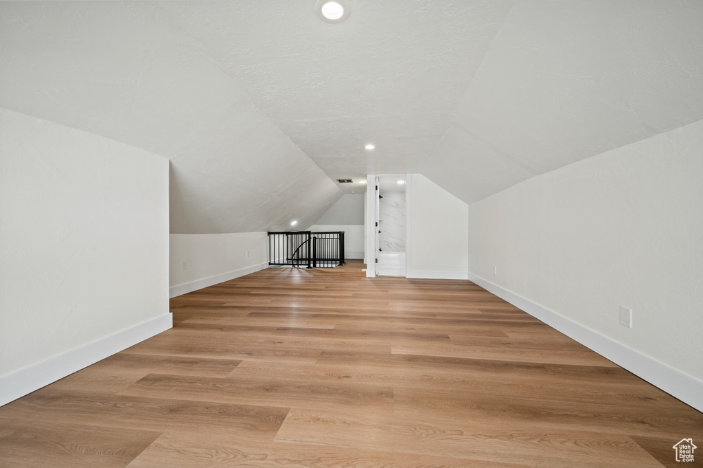 Bonus room with vaulted ceiling and light wood-type flooring