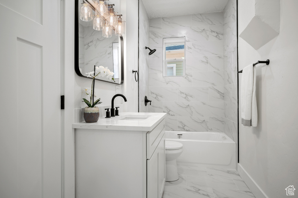 Bathroom with vanity, marble look tiles, and washtub / shower combination