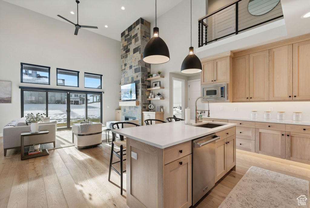 Kitchen with sink, light brown cabinets, a towering ceiling, and appliances with stainless steel finishes