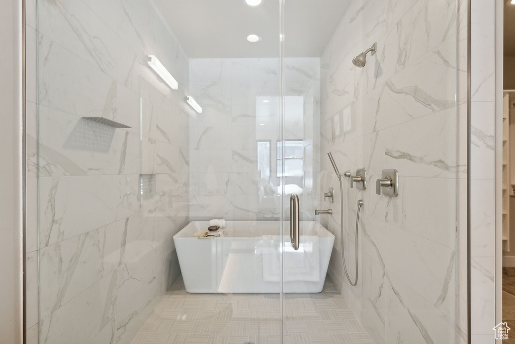 Bathroom featuring shower with separate bathtub, tile walls, and tile patterned floors