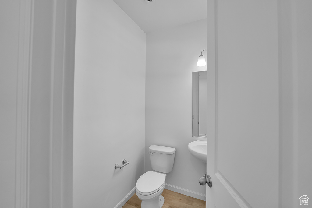Bathroom featuring toilet, wood finished floors, and baseboards