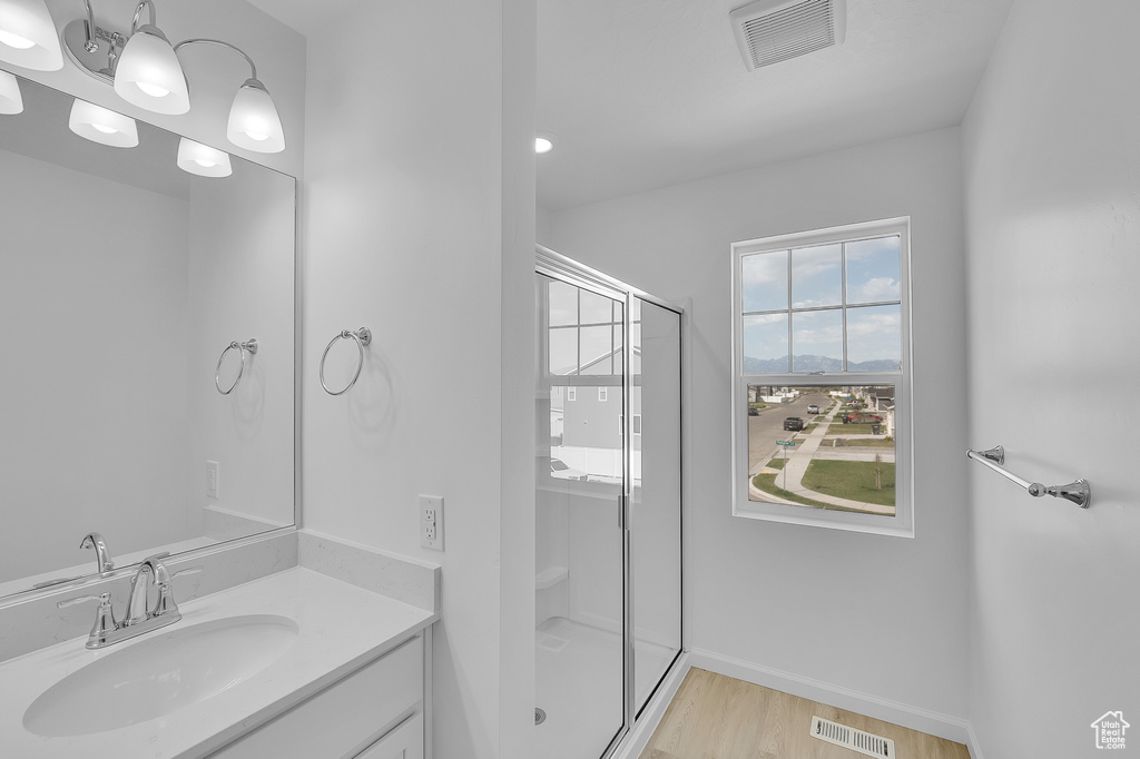Bathroom featuring a shower stall, vanity, wood finished floors, and baseboards