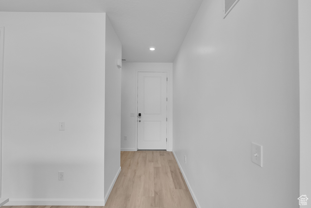 Hallway with light wood finished floors, baseboards, and recessed lighting