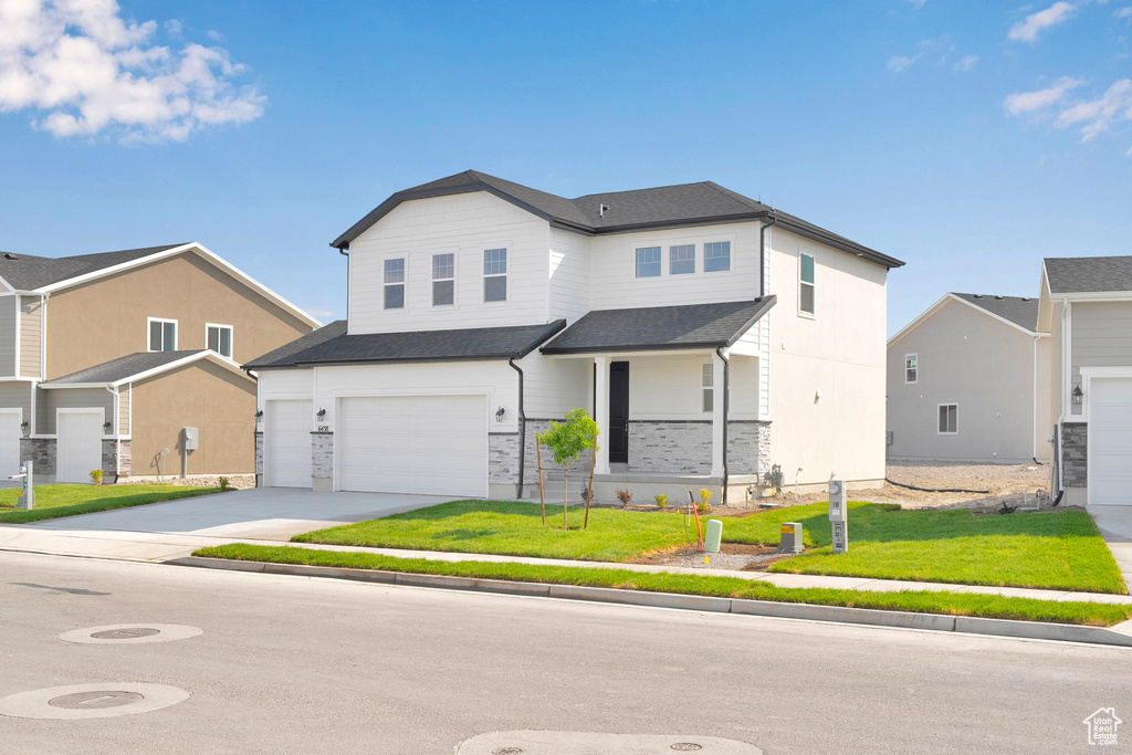 View of front of property with an attached garage, concrete driveway, a front yard, and roof with shingles