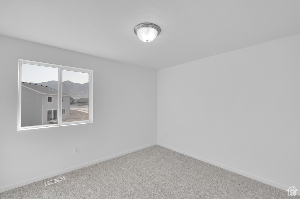 Carpeted spare room with baseboards and a mountain view