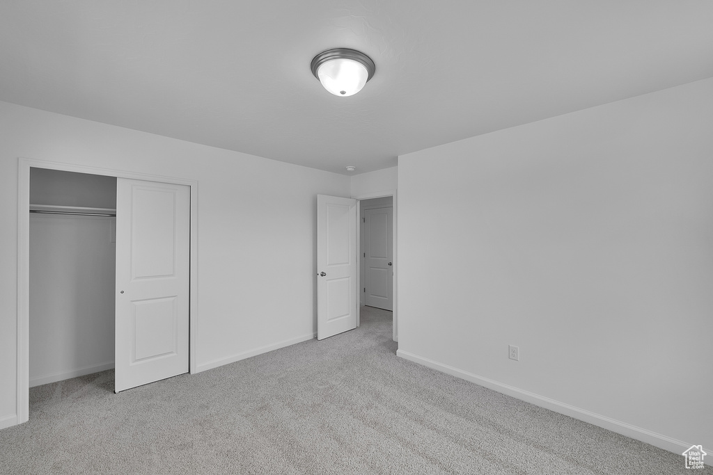 Unfurnished bedroom with carpet floors, baseboards, and a closet
