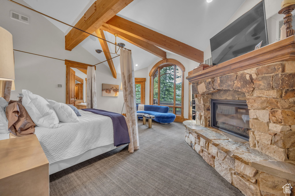 Carpeted bedroom with beam ceiling, a stone fireplace, and high vaulted ceiling