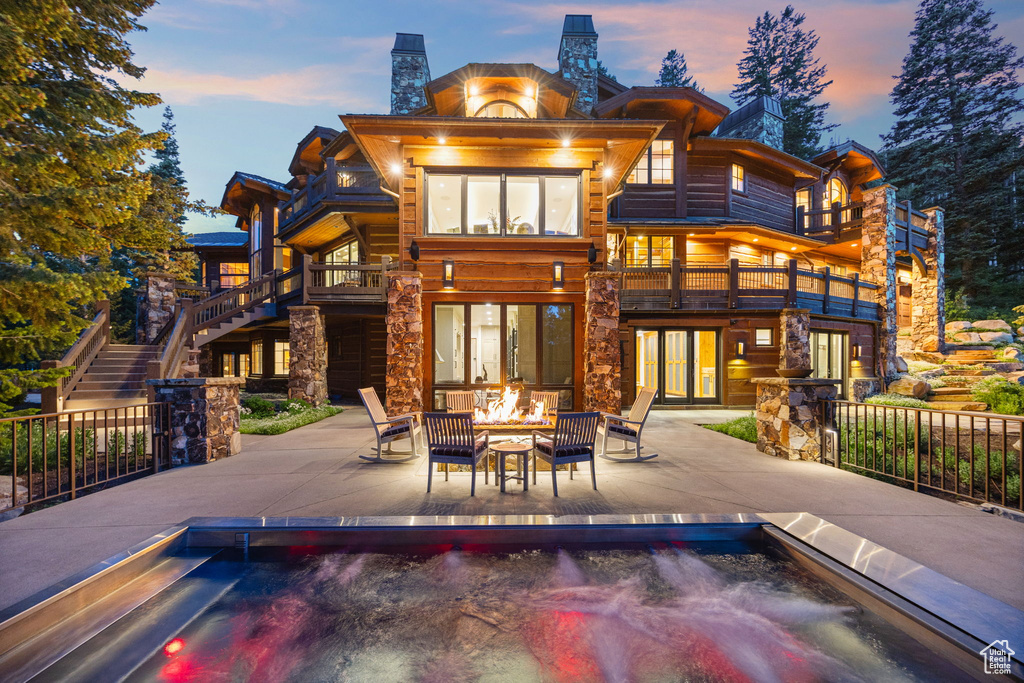 Back of property at dusk with stairway, a fire pit, a patio, and a chimney