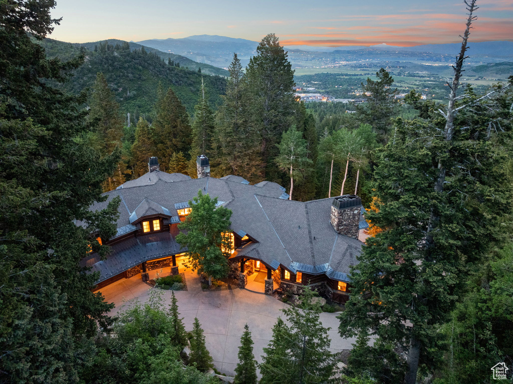 Aerial view of property and surrounding area with a mountain backdrop and a forest