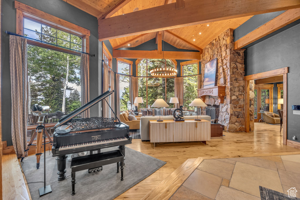 Living area with a wood ceiling with exposed beams, high vaulted ceiling, a chandelier, and wood finished floors