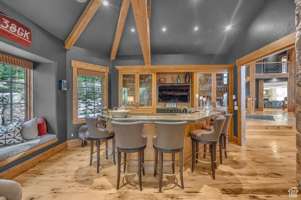 Indoor wet bar featuring beamed ceiling, light wood-style flooring, recessed lighting, and high vaulted ceiling