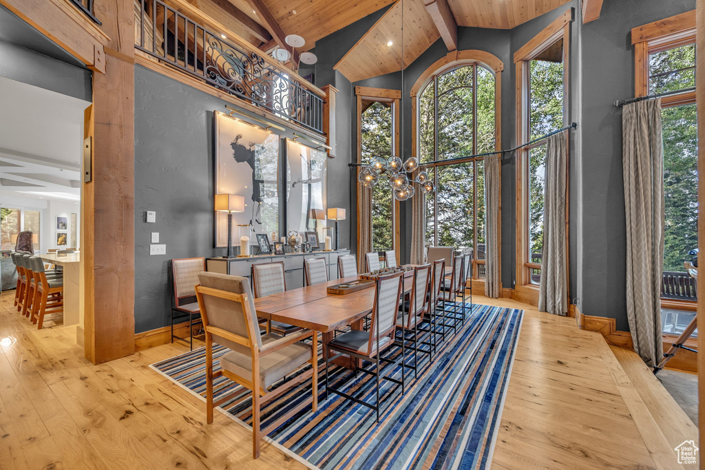 Dining area featuring high vaulted ceiling, hardwood / wood-style floors, a chandelier, and a wood ceiling with exposed beams