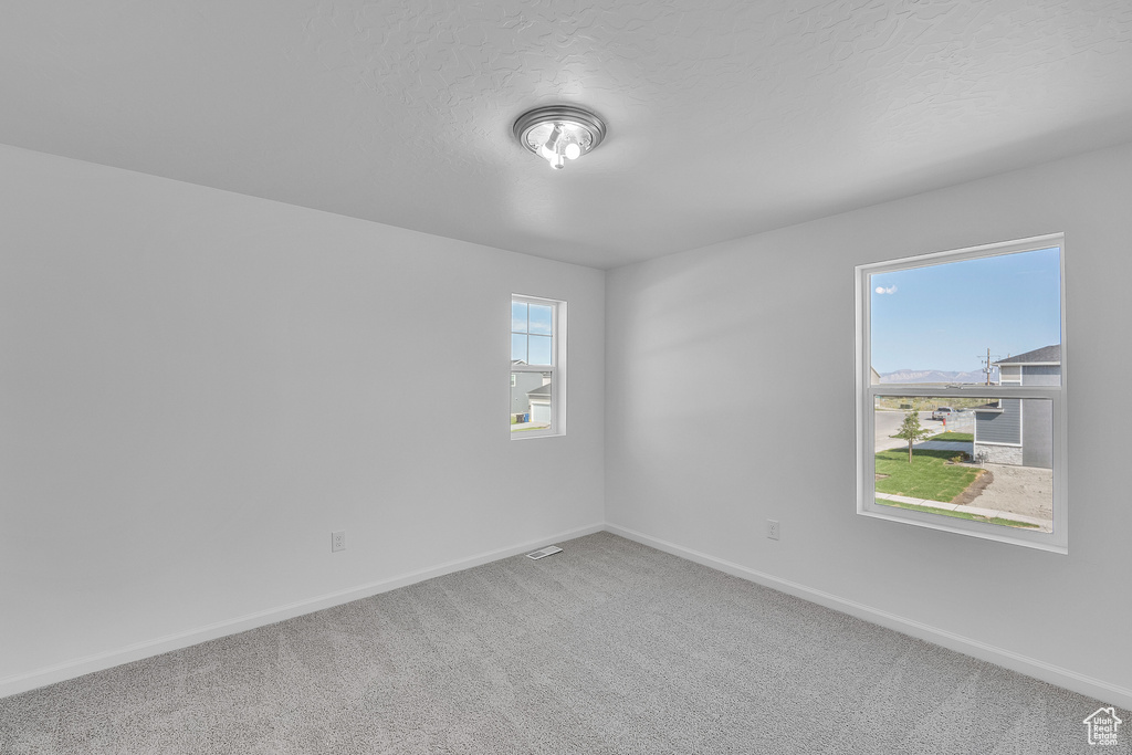 Carpeted empty room featuring baseboards and a textured ceiling