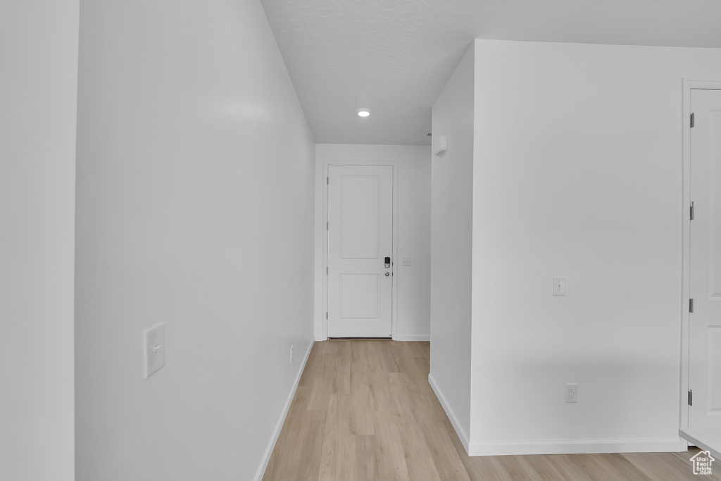 Corridor featuring light wood-style flooring, baseboards, and recessed lighting