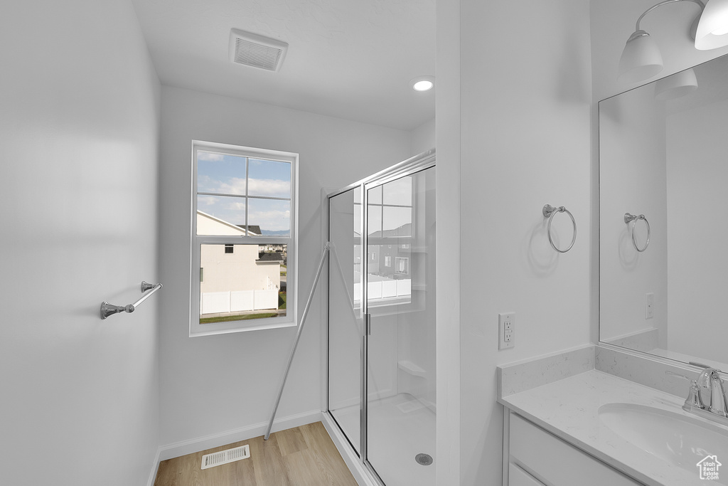 Full bath with vanity, a shower stall, wood finished floors, and baseboards