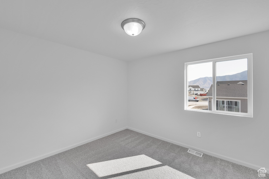 Carpeted spare room featuring baseboards and a mountain view