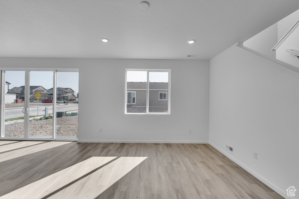 Spare room with wood finished floors, baseboards, recessed lighting, and stairs
