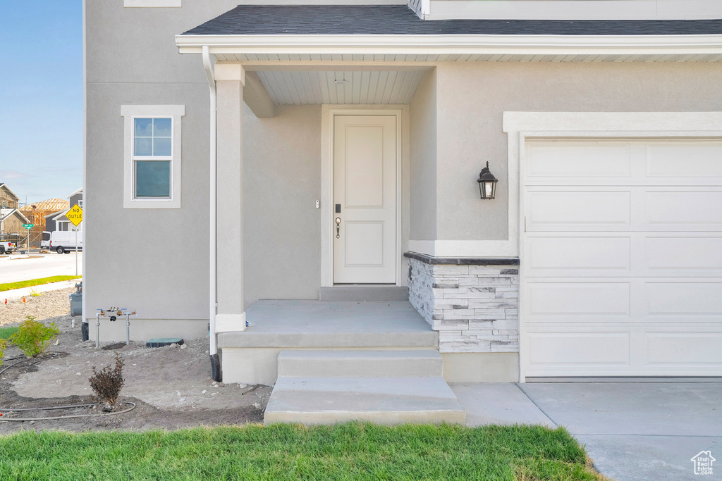 Entrance to property with stucco siding, roof with shingles, and stone siding