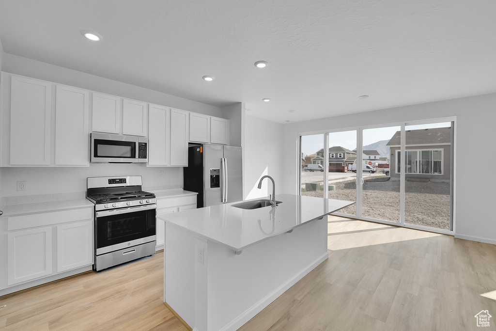Kitchen with stainless steel appliances, a sink, white cabinets, and recessed lighting