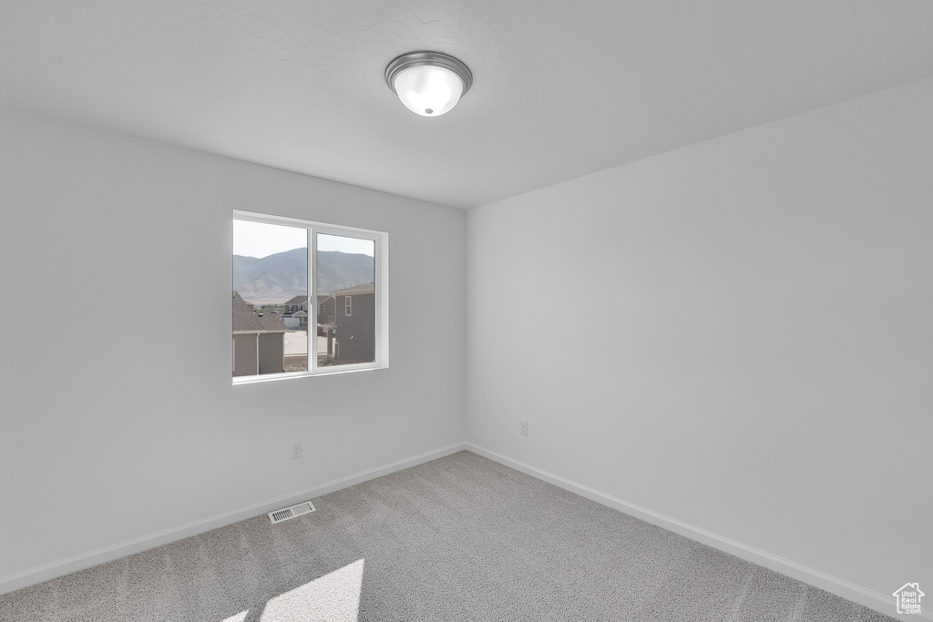 Spare room featuring baseboards, carpet, and a mountain view