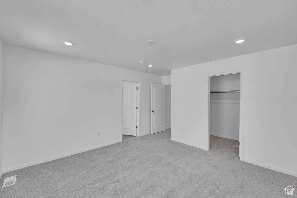Unfurnished bedroom with carpet, recessed lighting, baseboards, and a walk in closet