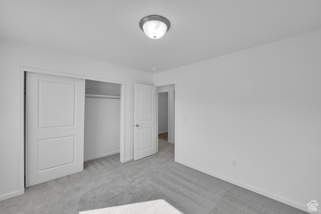Unfurnished bedroom with carpet floors, a closet, and baseboards