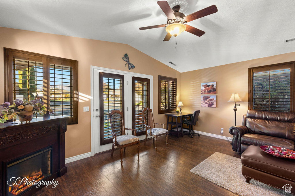 Living room with vaulted ceiling, ceiling fan, and dark hardwood / wood-style floors