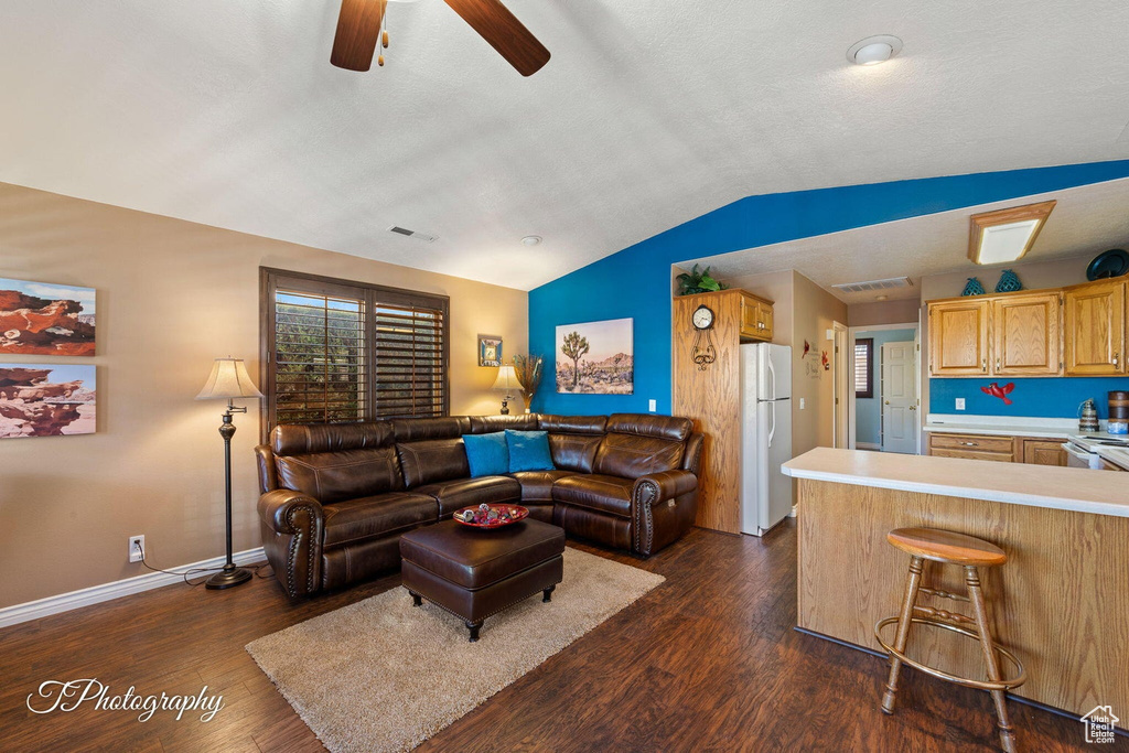 Living room with ceiling fan, lofted ceiling, and dark hardwood / wood-style floors