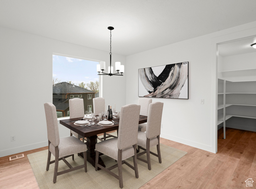 Dining area featuring an inviting chandelier, visible vents, light wood-style flooring, and baseboards