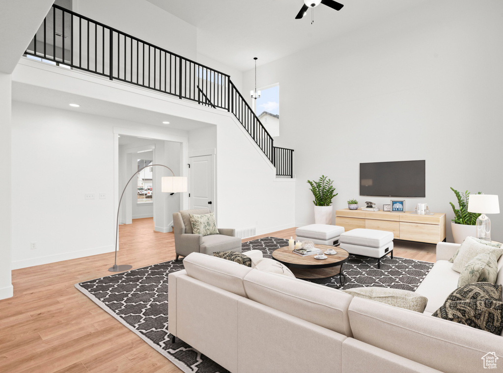 Living area featuring stairs, ceiling fan, a high ceiling, and wood finished floors