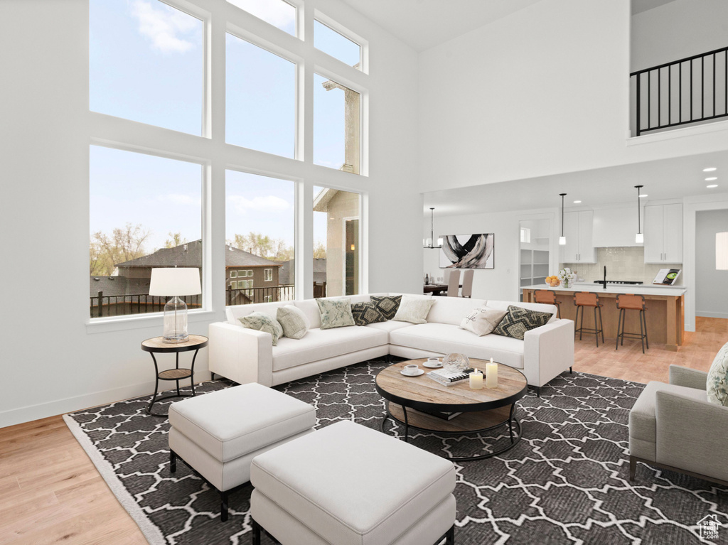 Living room with a towering ceiling, light wood finished floors, and baseboards