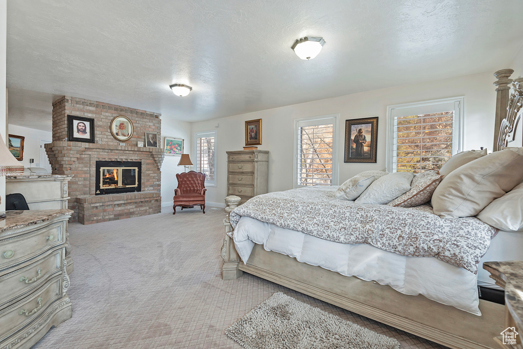 Carpeted bedroom featuring a textured ceiling and a brick fireplace