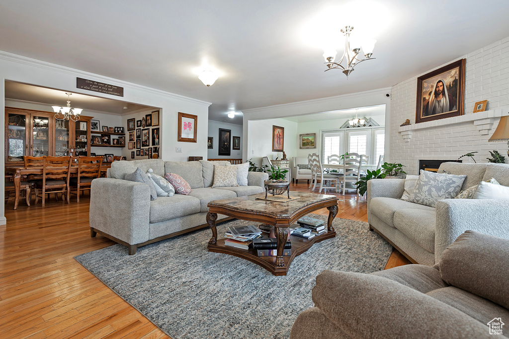 Living room with hardwood / wood-style flooring, a brick fireplace, ornamental molding, and brick wall