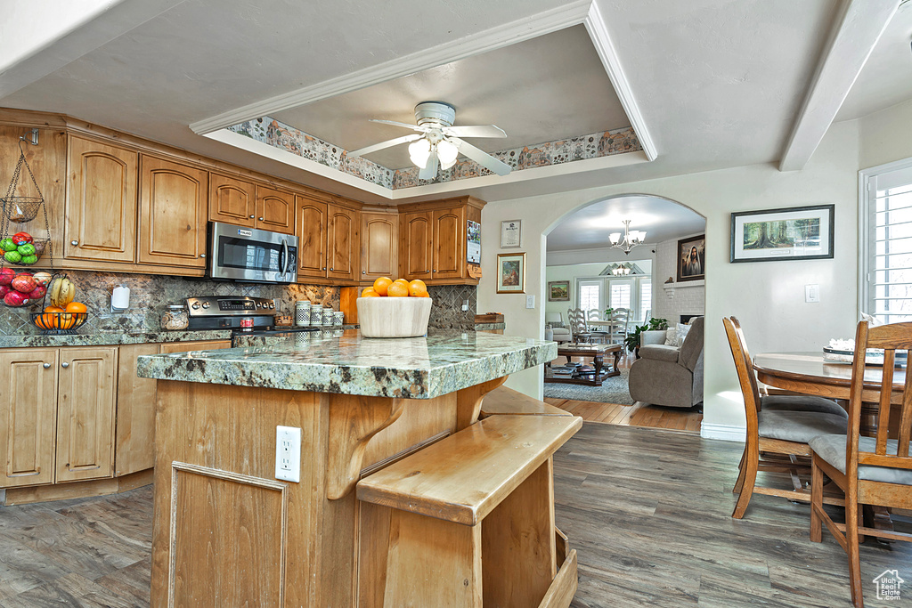 Kitchen with decorative backsplash, a kitchen island, stainless steel appliances, and ceiling fan with notable chandelier