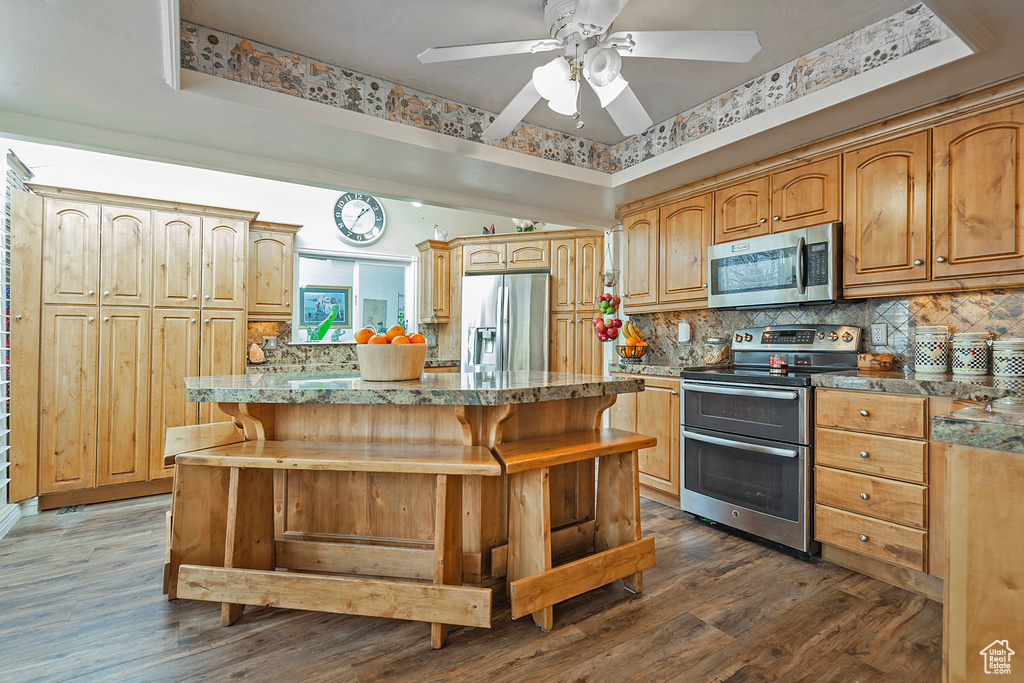 Kitchen featuring a kitchen bar, a kitchen island, dark wood-type flooring, and appliances with stainless steel finishes