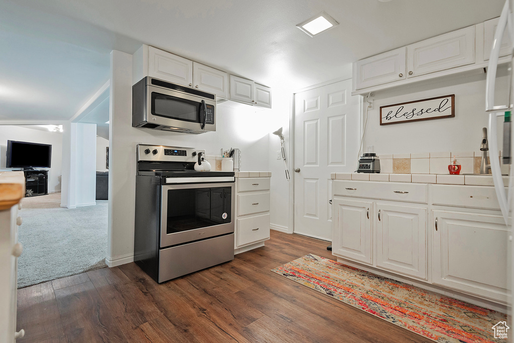 Kitchen with dark hardwood / wood-style floors, white cabinetry, and stainless steel appliances