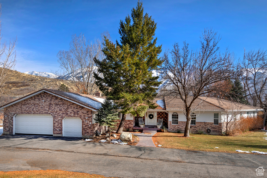 View of front of house featuring a mountain view, a garage, and a front lawn