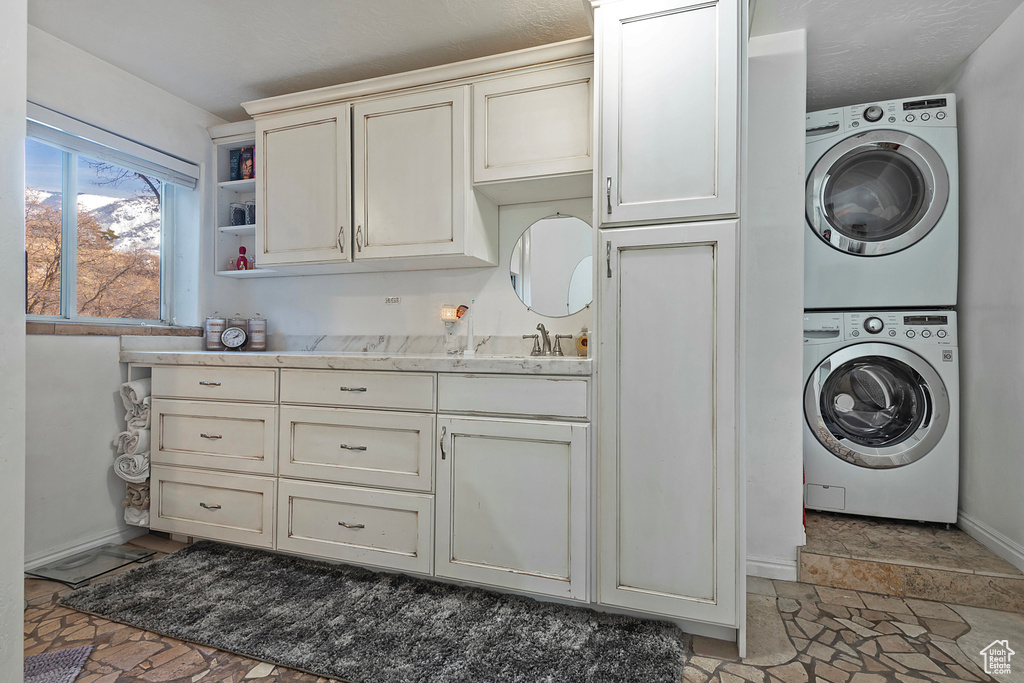 Laundry room with cabinets and stacked washer and dryer