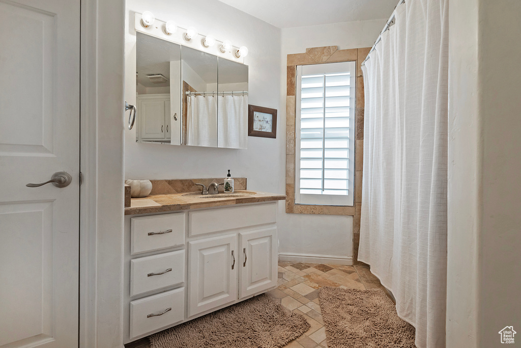 Bathroom featuring a shower with shower curtain, vanity, and plenty of natural light