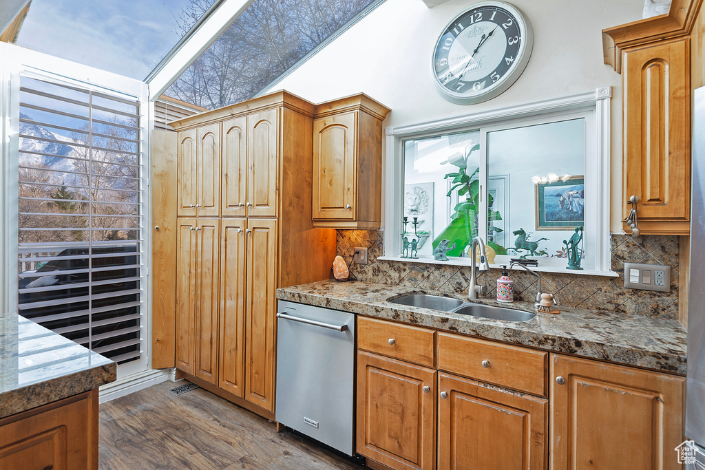 Kitchen with light stone countertops, sink, tasteful backsplash, dark hardwood / wood-style flooring, and stainless steel dishwasher