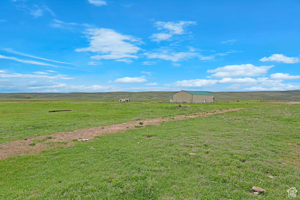 View of green lawn featuring a view of rural / pastoral area and an outbuilding