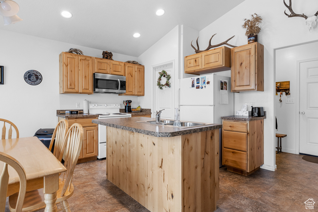 Kitchen with sink, light brown cabinets, white appliances, and a center island
