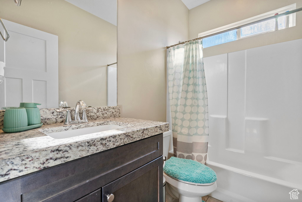 Full bathroom with toilet, shower / bath combination with curtain, and vanity