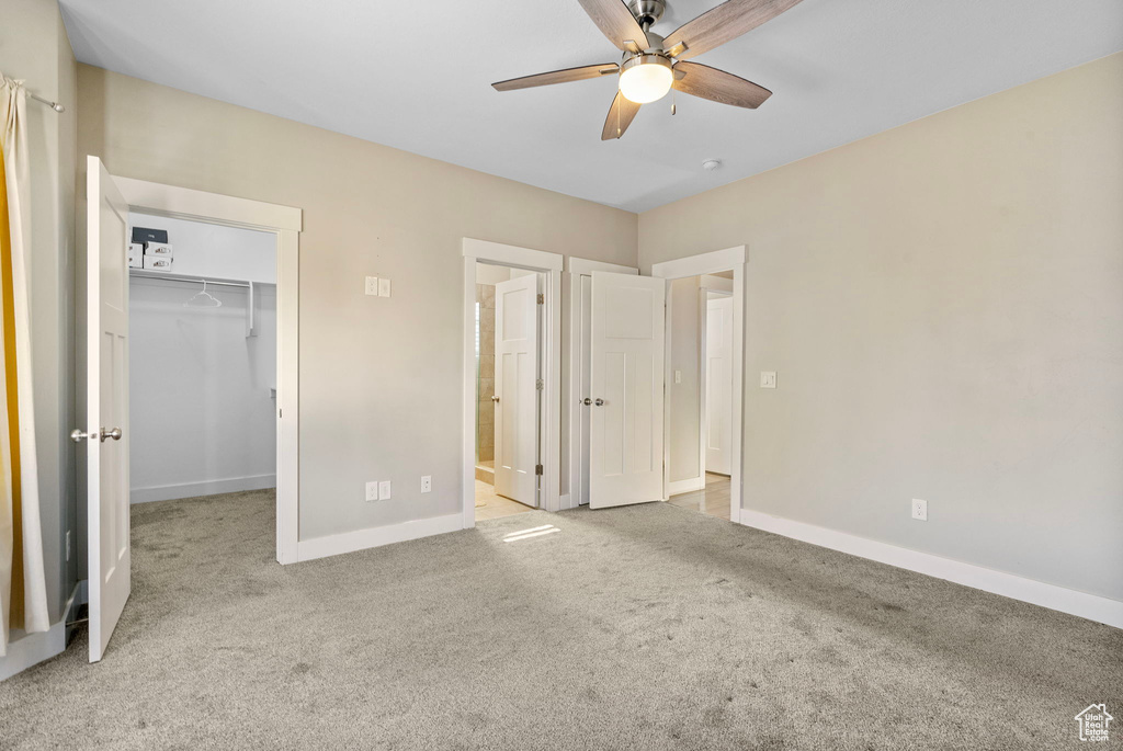 Unfurnished bedroom with ceiling fan, light colored carpet, a closet, and a walk in closet