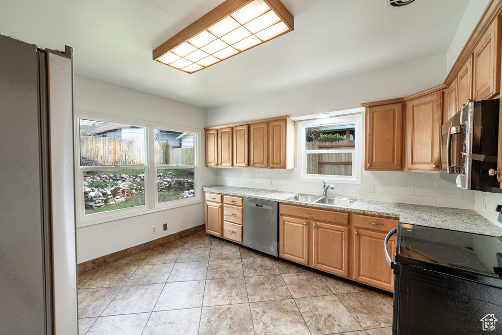 Kitchen featuring tasteful backsplash, sink, light tile patterned flooring, stainless steel appliances, and light stone counters