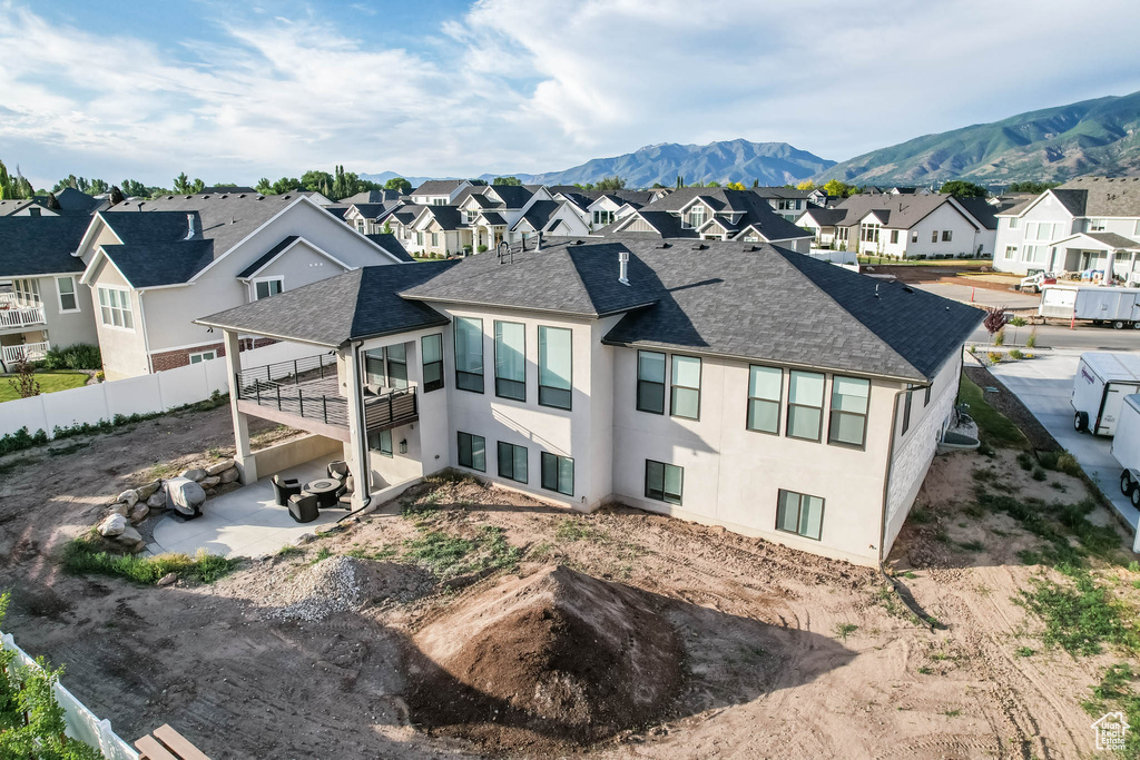 Rear view of property with a residential view, a patio area, a shingled roof, a mountain view, and stucco siding