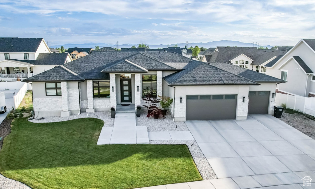 View of front of house with a garage, driveway, a residential view, and a mountain view