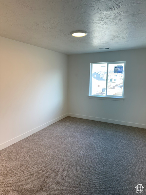 Spare room featuring a textured ceiling and carpet